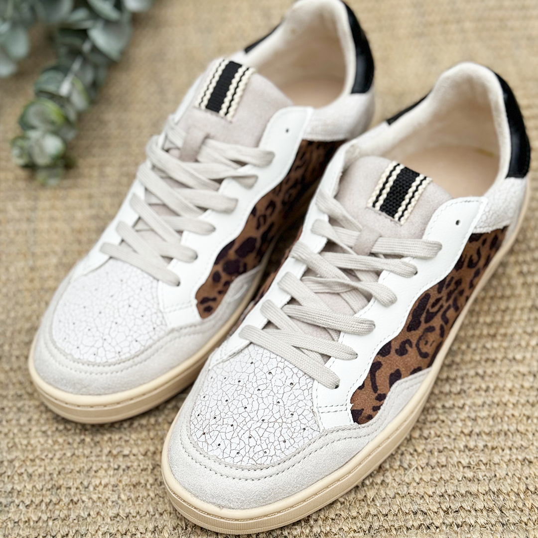 Un par de zapatillas color blanco con print de leopardo en los lados.